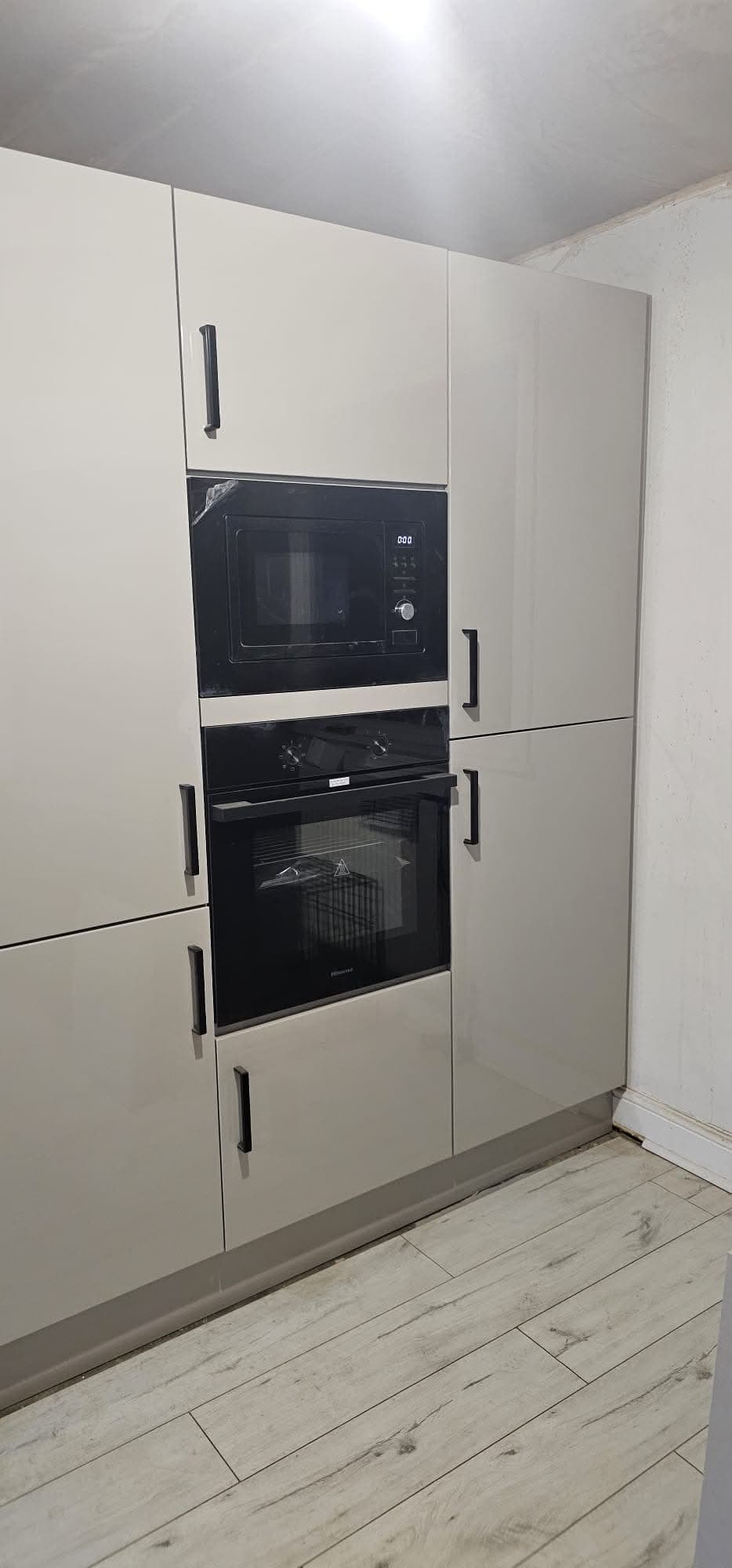 Cream painted kitchen tall unit with integrated double black oven and microwave, stainless steel handles.